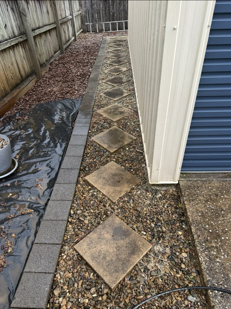 A stepping-stone garden path dirty and mossy before pressure washing